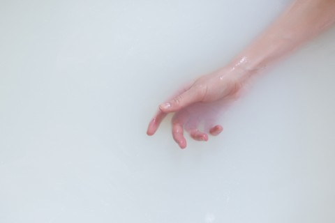 Hand of Caucasian woman in the milk bath