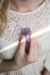 Caucasian woman holding crystal to heart