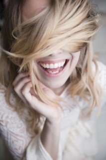 Laughing Caucasian woman covering eyes with hair