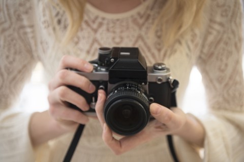 Hands of Caucasian woman focusing lens on camera
