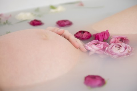 Caucasian expectant mother in milk bath with flowers