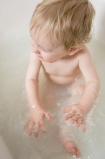 Caucasian baby boy splashing in milk bath