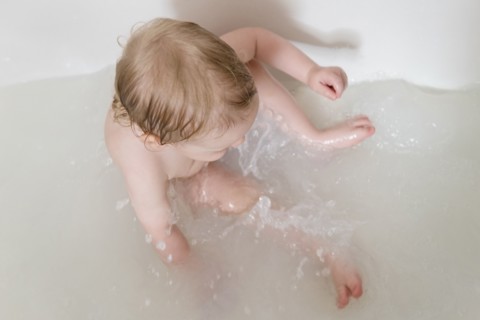 Caucasian baby boy splashing in the bathtub