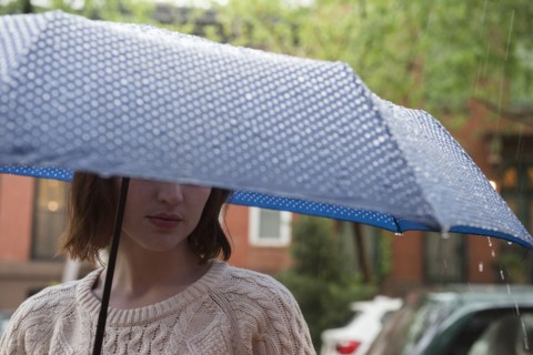 Caucasian woman holding an umbrella in rain