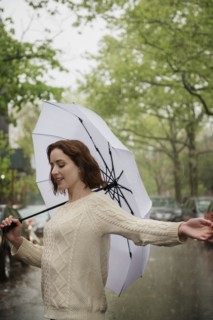 Carefree Caucasian woman holding an umbrella in the rain