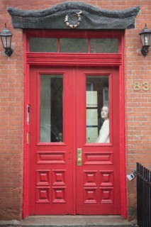 Caucasian woman daydreaming behind red door