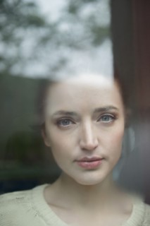 Serious Caucasian woman behind foggy window