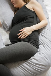 Caucasian expectant mother laying on bed with support pillow