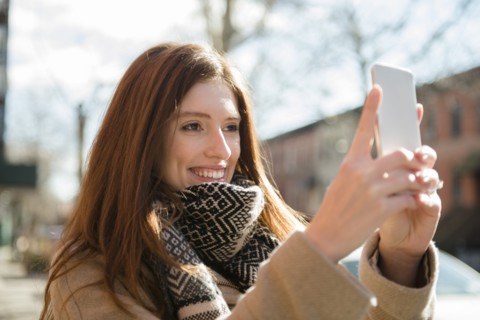 Caucasian woman wearing scarf posing for cell phone selfie