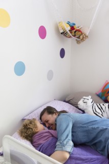 Caucasian mother and daughter laughing and cuddling in bed