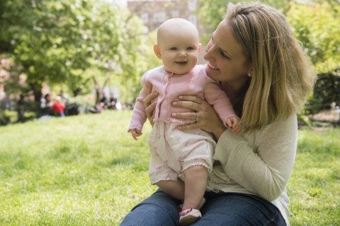 Portrait of Caucasian mother holding baby daughter in park