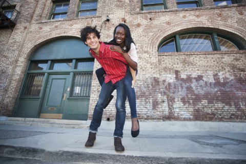 Boyfriend giving girlfriend piggyback ride in urban area