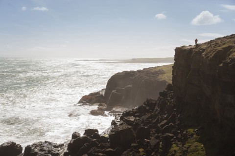 Chinese man standing on cliff at ocean