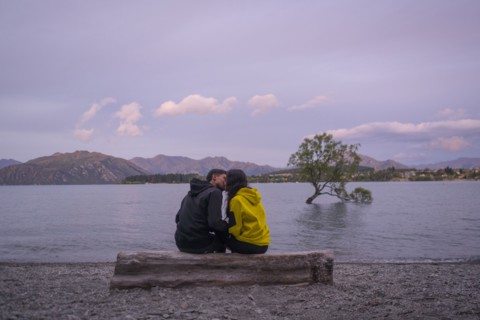 Mixed Race couple kissing on log at river