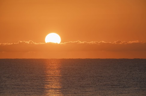Blazing sunrise in orange sky over ocean