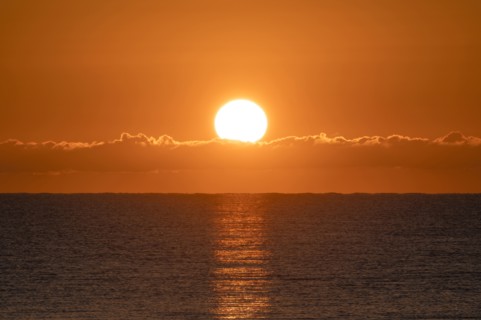 Blazing sunrise in orange sky over ocean