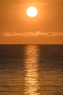 Blazing sunrise in orange sky over ocean