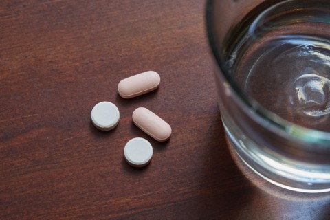 Overhead view of glass of water and pills on table