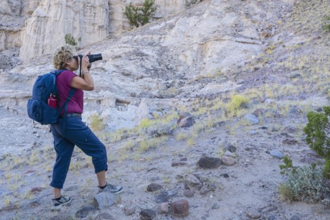 Woman with backpack photographing rocky landscape