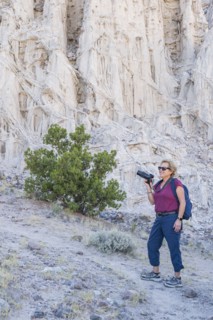 Woman with backpack and camera hiking in rocky landscape