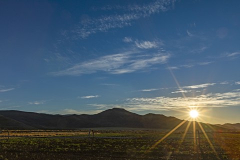 Sun rising over fields and hills