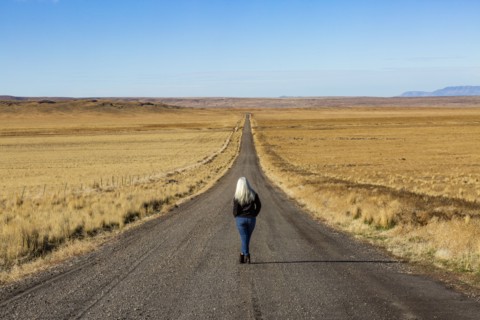 Senior woman walking down desert road