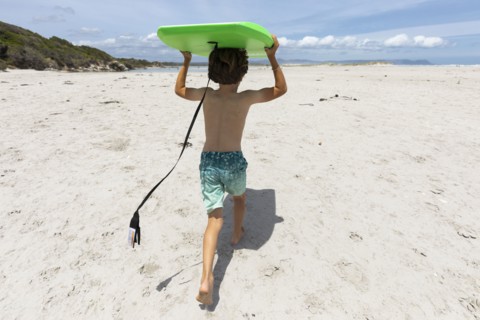 Boy with surfboard on beach