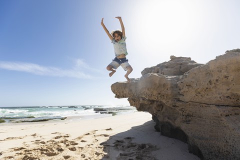 Boy jumping off rock