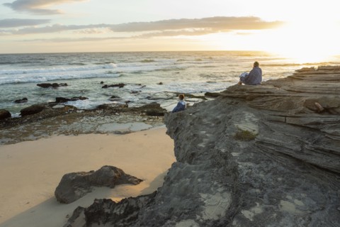 Mother and daughter sitting on beach