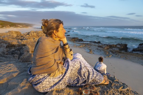 Woman sitting on beach looking at ocean