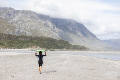 Boy carrying bodyboard on beach
