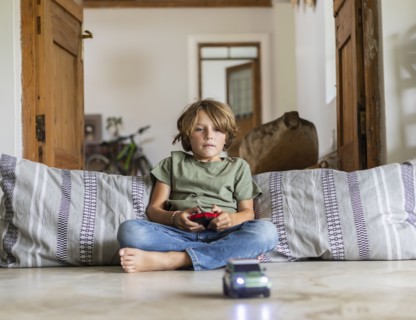 Boy playing with remote-control toy car at home
