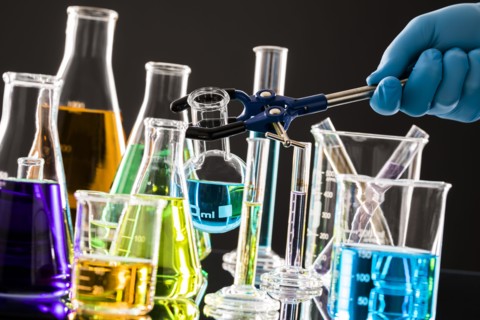 Chemist combining colorful liquids in laboratory glassware