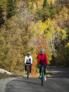 Smiling man and woman riding bicycles on country road