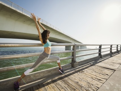 Woman stretching on bridge on sunny day