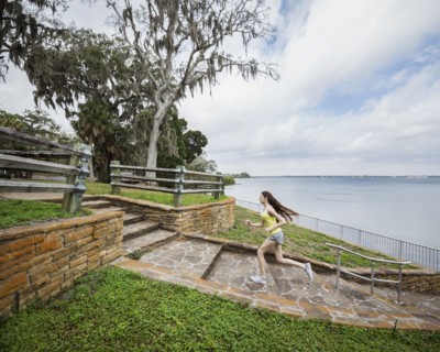 Athlete woman running up steps by river