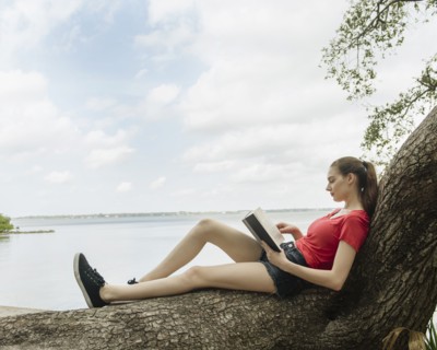 Woman sitting on tree and reading book