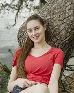 Portrait of smiling woman leaning against tree trunk
