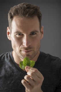 Studio portrait of man holding fresh mint leaves