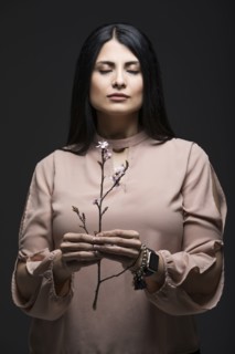 Studio portrait of woman holding blooming twig with eyes closed