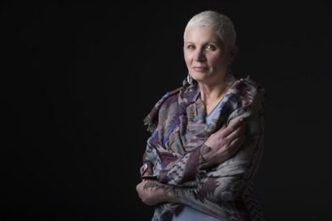Studio portrait of woman with white short hair wrapped in shawl