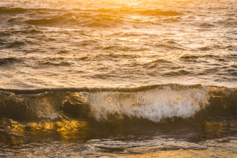 Ocean waves splashing at sunset