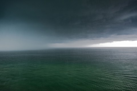 Thunder storm clouds and rain over ocean