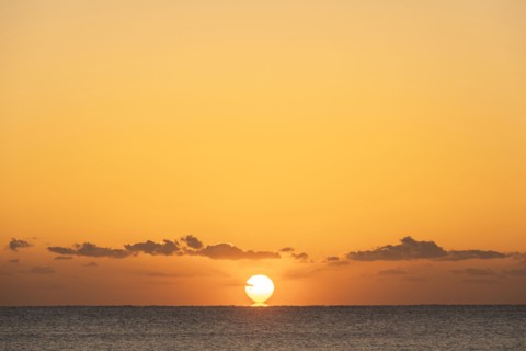 Sun rising above calm ocean