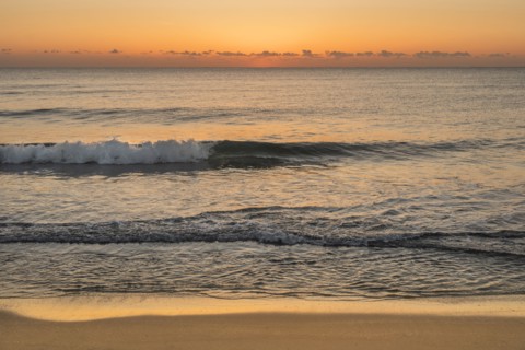 Ocean waves on beach at sunrise