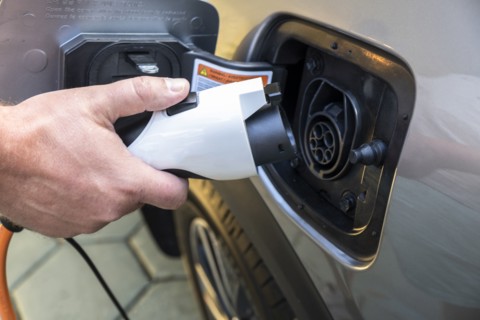 Mans hand holding charge cable in electric vehicle