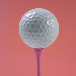 Golf ball on tee against pink background