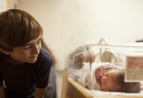 Boy (12-13) looking at newborn baby sister (0-1 months) in incubator