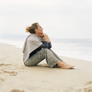 Woman sitting on beach looking at ocean