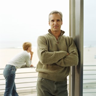 Portrait of man leaning on doorway of house